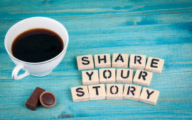 share your story. Coffee mug and wooden letters on wooden background.